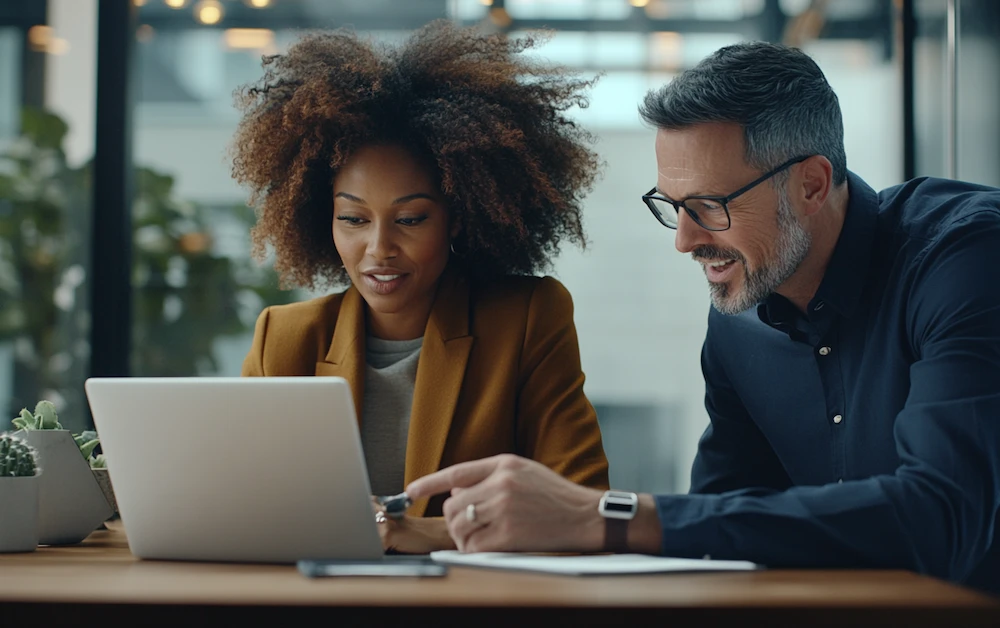 Business professionals discussing RPA challenges while analyzing automation software on a laptop in a modern office. Overcoming robotic process automation obstacles in finance and operations.