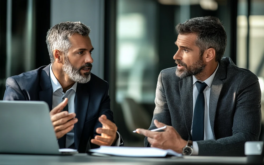 Two finance professionals discussing securitization strategies in a modern office. They analyze risk management, asset-backed securities, and financial structuring for securitization deals.