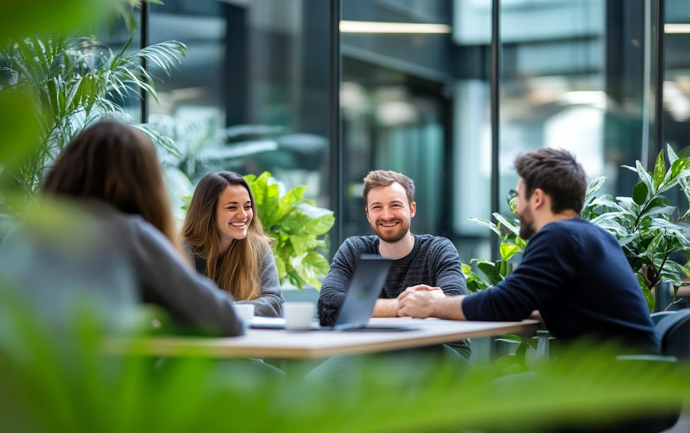 Team collaborating on finance process transformation in a modern office with greenery, discussing digital tools and automation strategies to improve financial workflows.