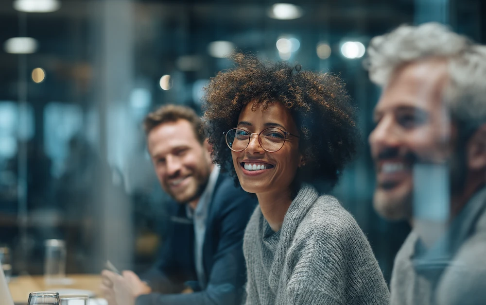 Diverse professionals in a modern office smiling during a financial technology strategy meeting, showcasing innovation and collaboration in fintech.