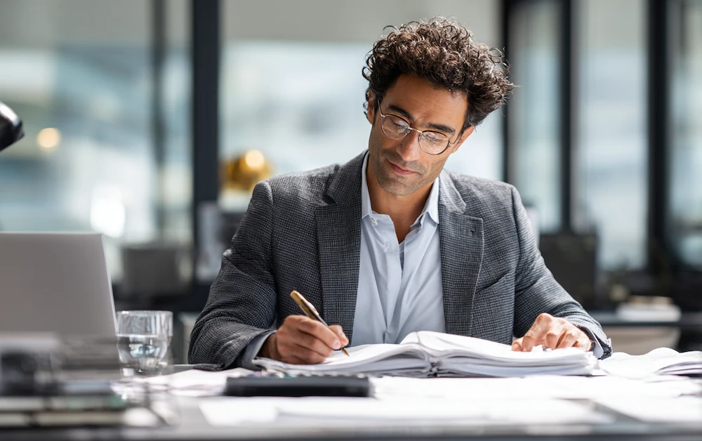 Finance professional performing GL reconciliation at a modern office desk, reviewing financial statements and journal entries with focus and precision.