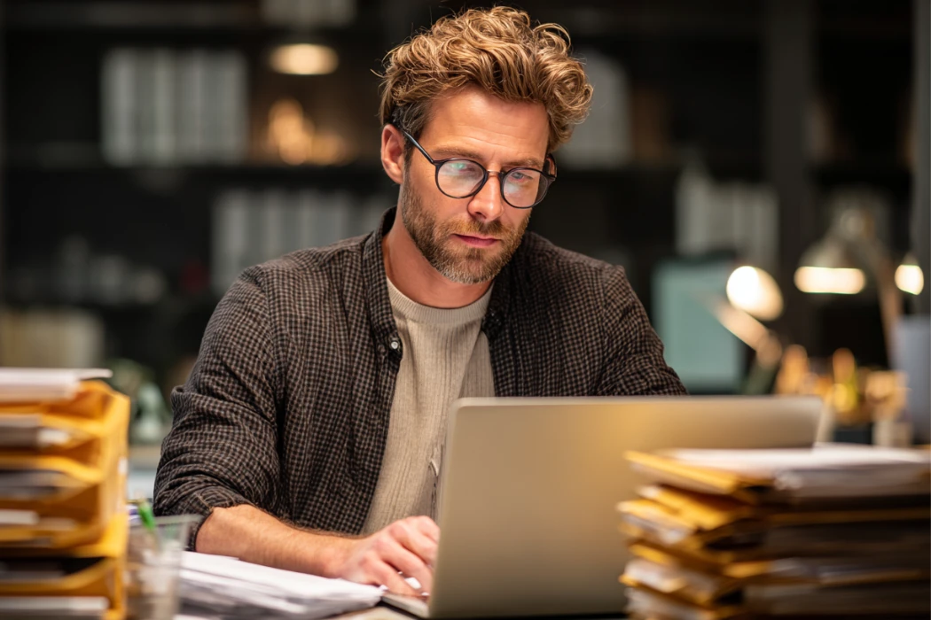 Accountant working late on a laptop to complete the monthly close process accounting, organizing financial records, reconciling accounts, and preparing accurate month-end reports.