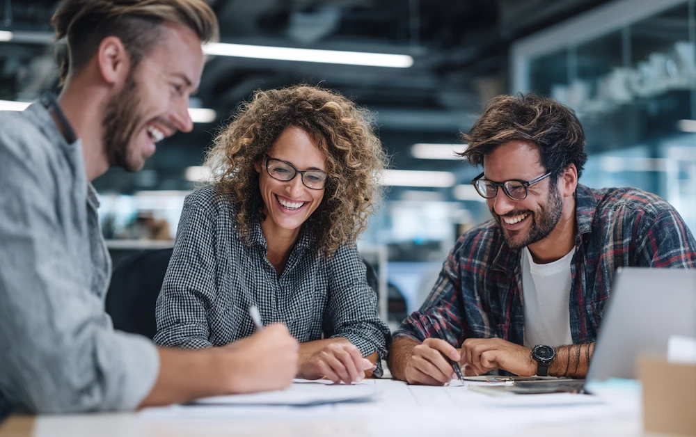 Finance team collaborating on cost accounting strategies at a modern office workspace, reviewing documents and budgeting data for accurate cost tracking and financial planning.