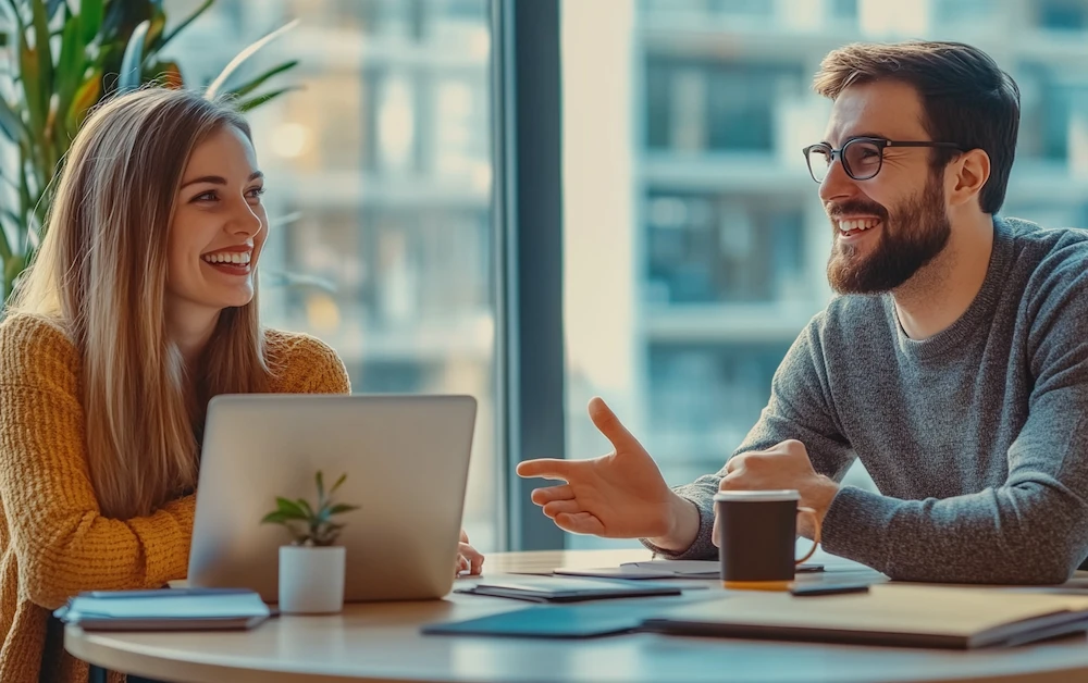 Two professionals discussing risk mitigation tools in a modern office, using a laptop and documents for strategic planning. Effective risk management solutions enhance financial security and operational efficiency.