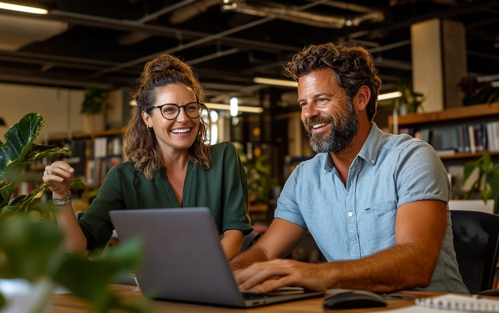Two finance professionals collaborating on back office finance automation in a modern office, using a laptop for automated reconciliation and reporting. Enhancing efficiency with digital finance tools.
