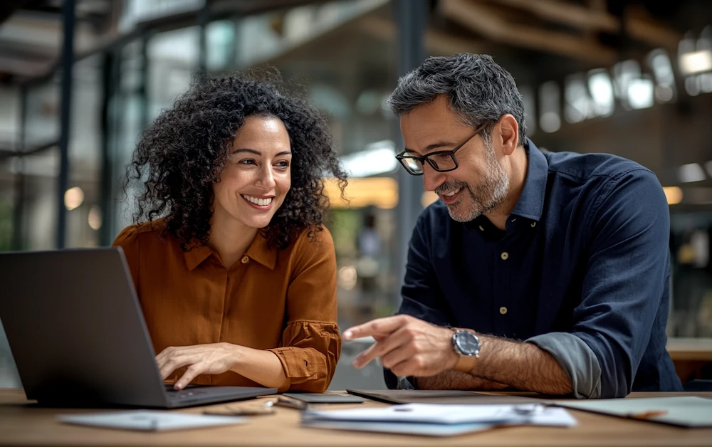 Two professionals discussing financial data on a laptop, highlighting the basic tools of accounting for efficient bookkeeping and financial management.