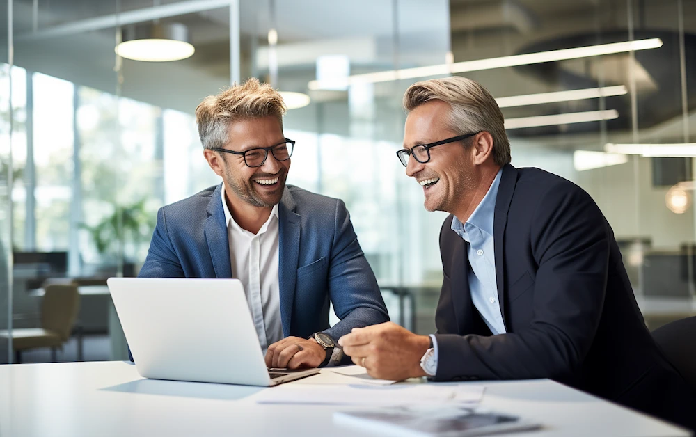 Business professionals reviewing financial data on a laptop using check scanning software for automated bank reconciliation in a modern office setting.