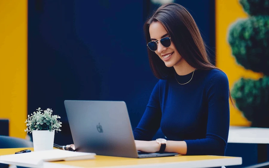 Professional woman smiling while using a laptop, representing the impact of low code automation on business processes.