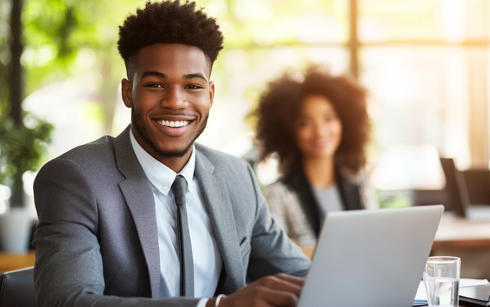 Business professional smiling while working on a laptop in a modern office, representing efficiency and accuracy through accounting process automation.