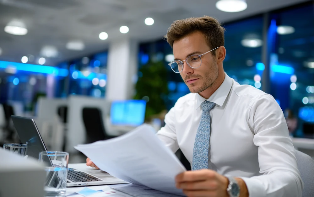 Business professional reviewing financial reports for balance sheet reconciliation, ensuring accurate account matching and compliance in a modern office environment.