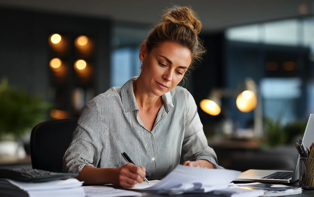 Focused accountant reviewing financial statements and reconciling account balances at her desk to ensure an accurate reconciled balance for monthly reporting.