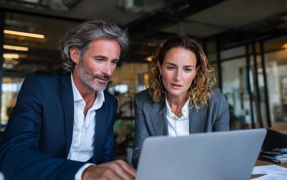 Finance professionals reviewing balance sheet reconciliation on a laptop in a modern office – demonstrating collaboration and accuracy in financial reporting