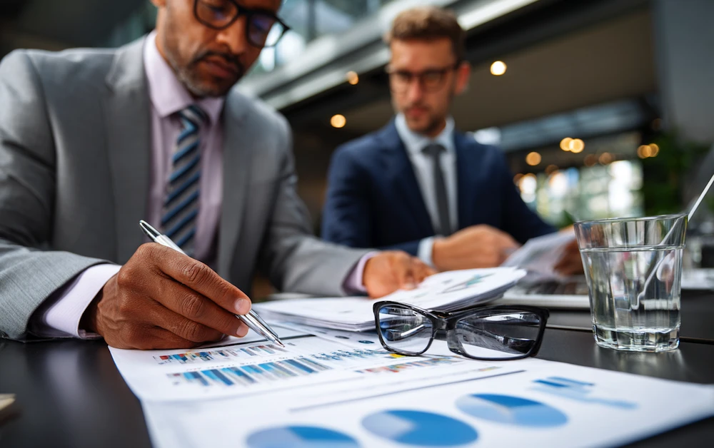 Finance professionals conducting an internal financial audit, reviewing charts and reports with data analysis documents in a modern office setting.