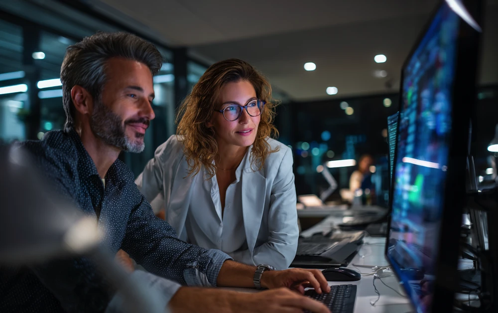 Finance professionals using a process automation tool to analyze data and improve workflow efficiency on computer screens in a modern office environment.