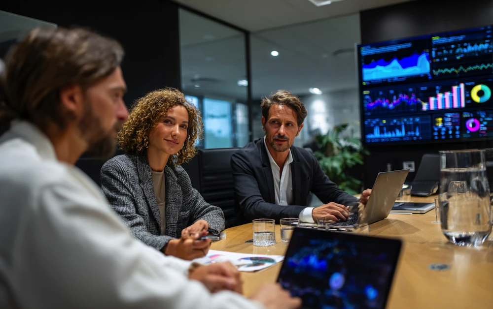 Finance professionals analyzing data dashboards and reports during a meeting focused on financial performance analysis and strategic decision-making.