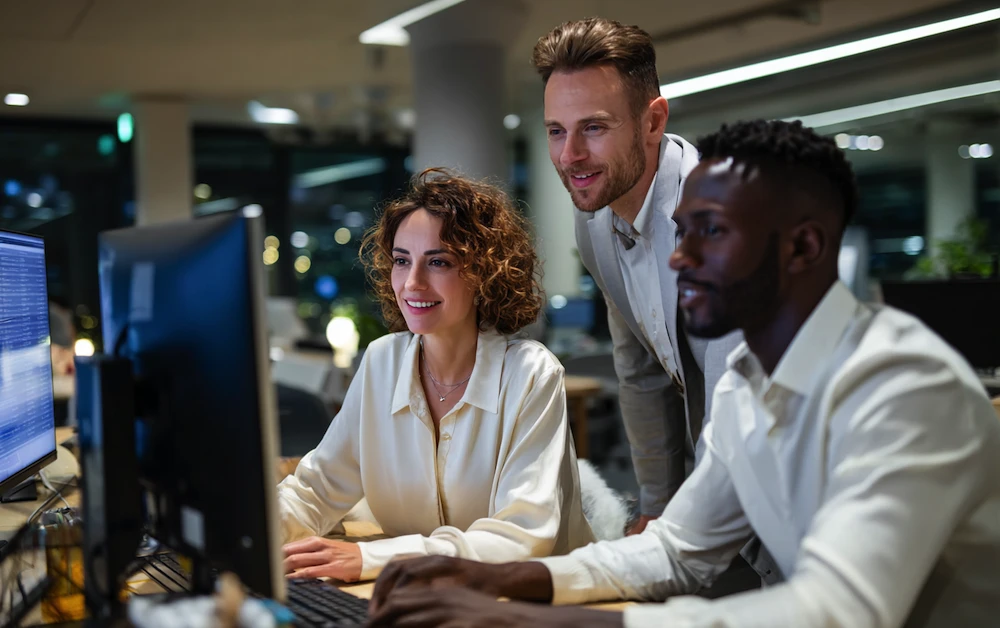 Finance team collaborating on computers using general ledger reconciliation software to automate account matching and ensure accurate financial reporting.
