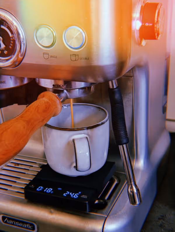 Kaffee wird in einer Siebträgermaschine gebrüht. Unter dem Siebträger steht eine Kaffeetasse auf einer Waage.