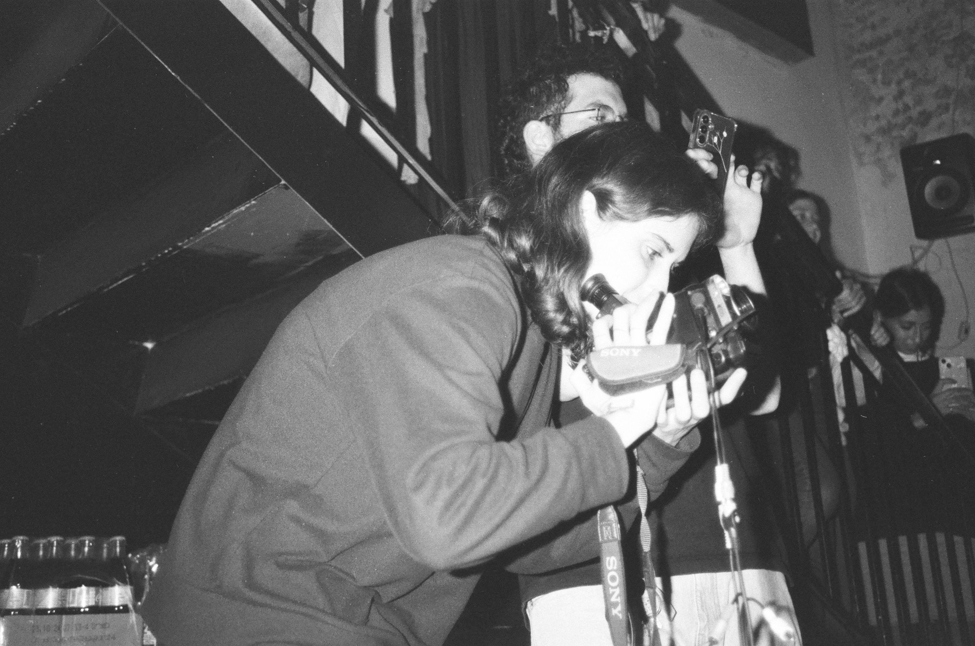 Live low‑light VHS‑style photo of a musician performing in a cozy flat living room