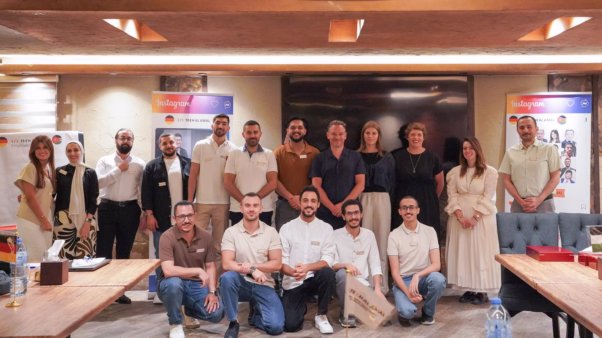Team of 17 people posing indoors with Instagram-themed banners behind them, some seated, others standing.
