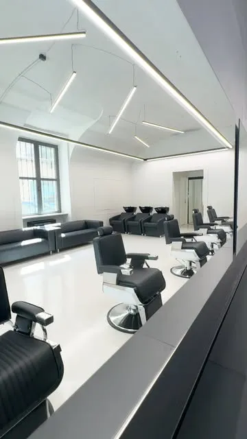 Il salone Cut Club: postazioni con poltrone nere, ampi specchi e soffitto a volta illuminato