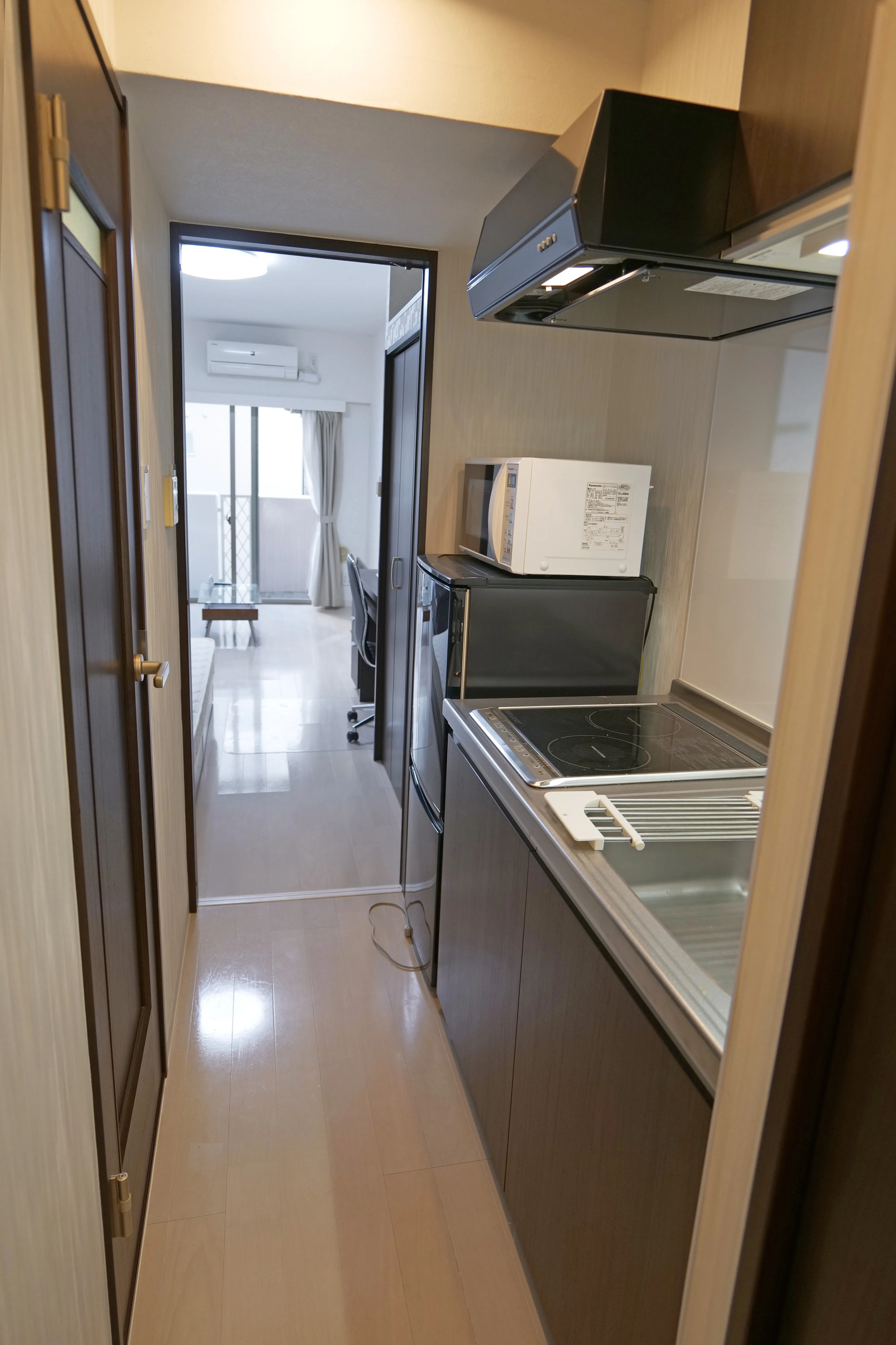 Functional kitchenette with induction stove, sink, and overhead/under-sink storage.