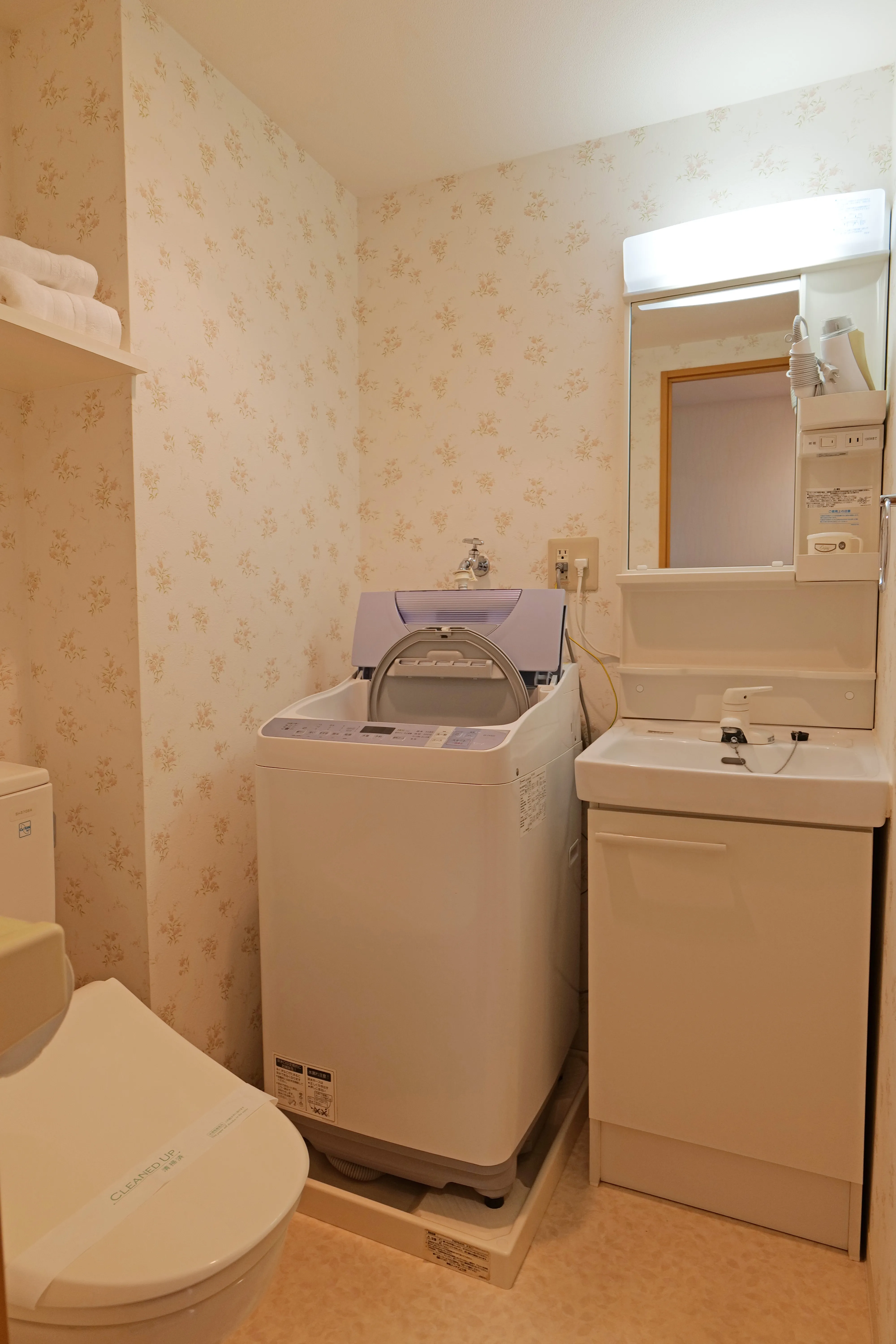 Bathroom with bidet toilet, wash-and-dry machine, and vanity sink with storage.