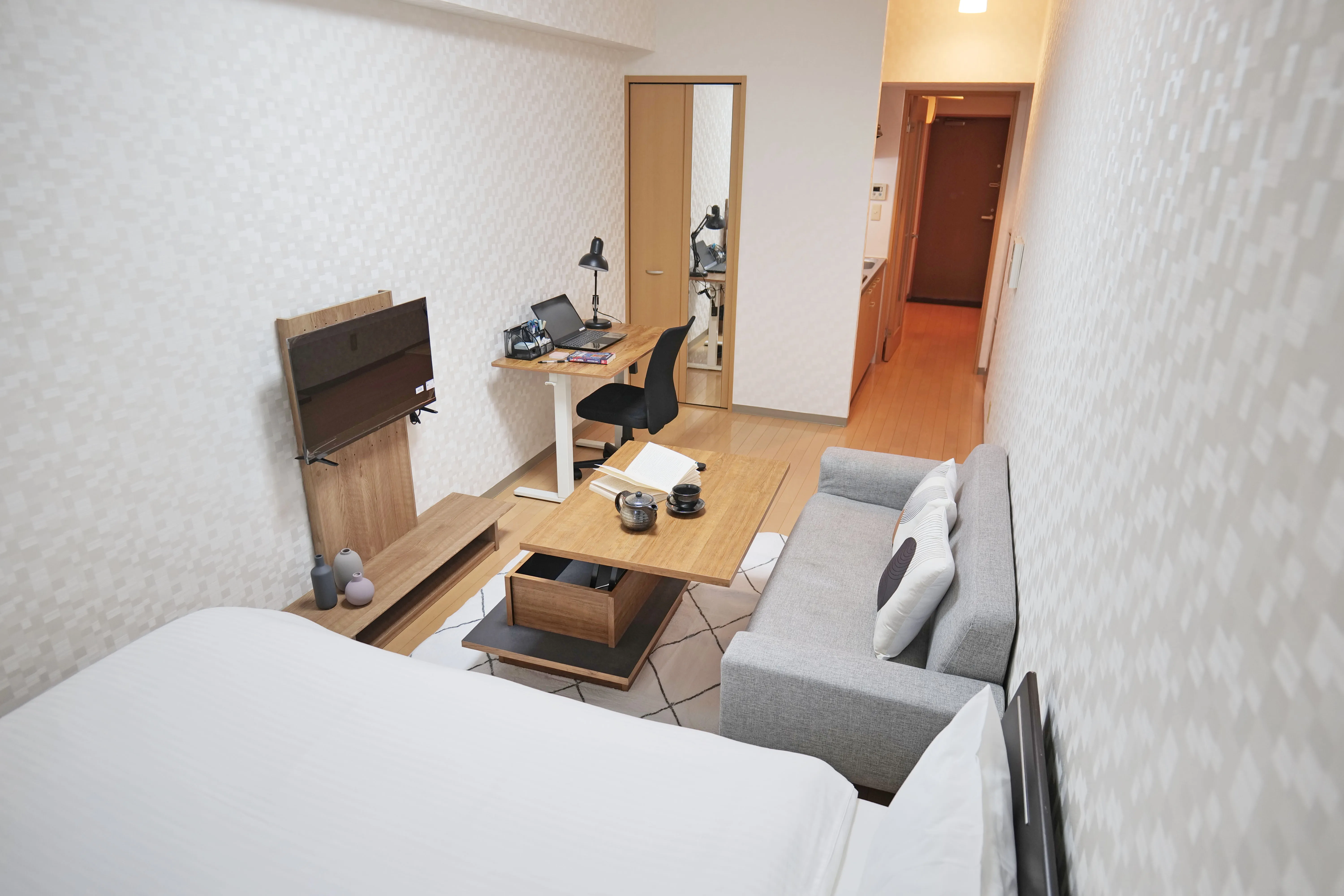 Cozy small bedroom with a semi-double bed, wooden floor, TV stand, and center table for comfortable city living.