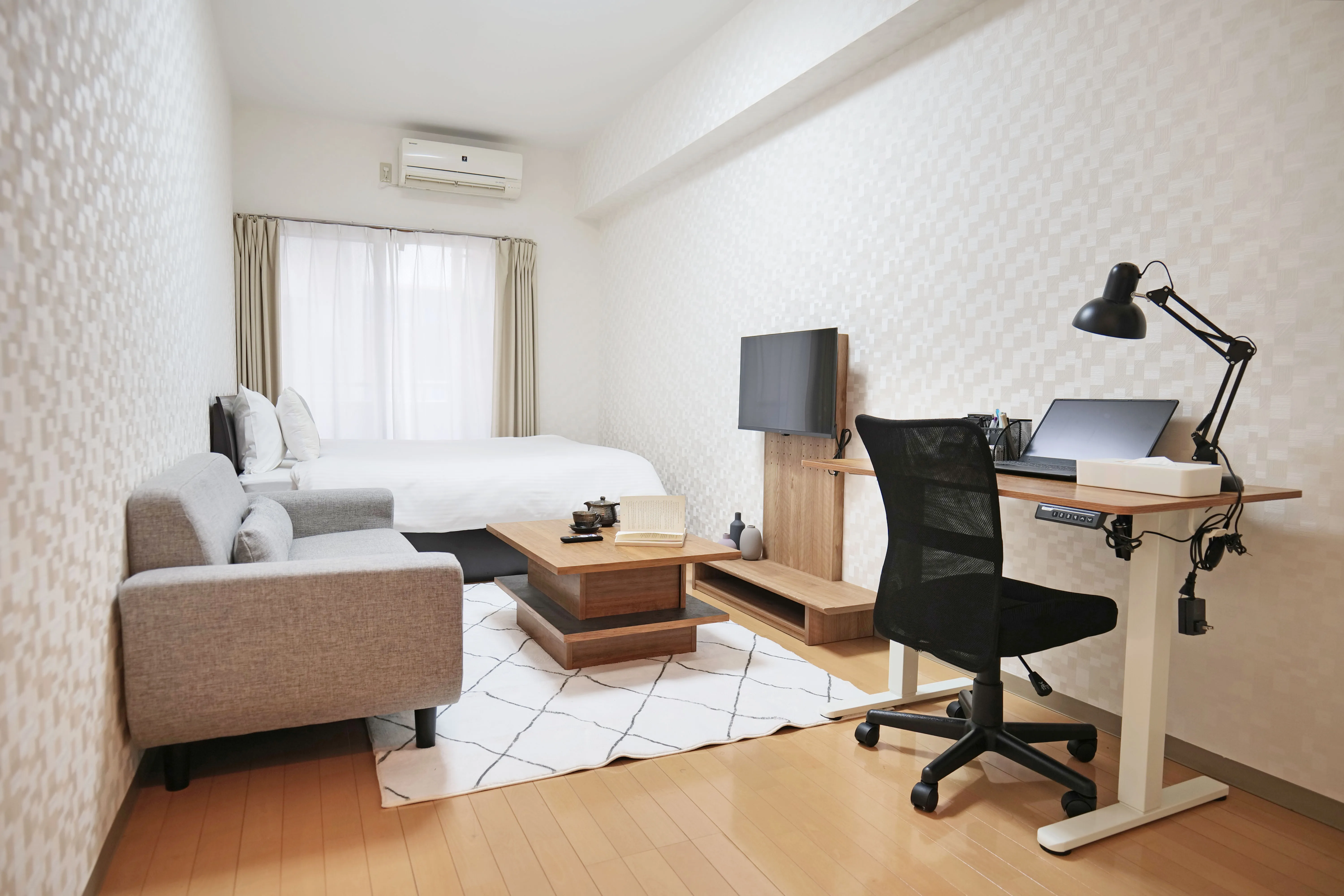 Cozy small bedroom with a double-sized bed, wooden floor, TV stand, and center table for comfortable city living