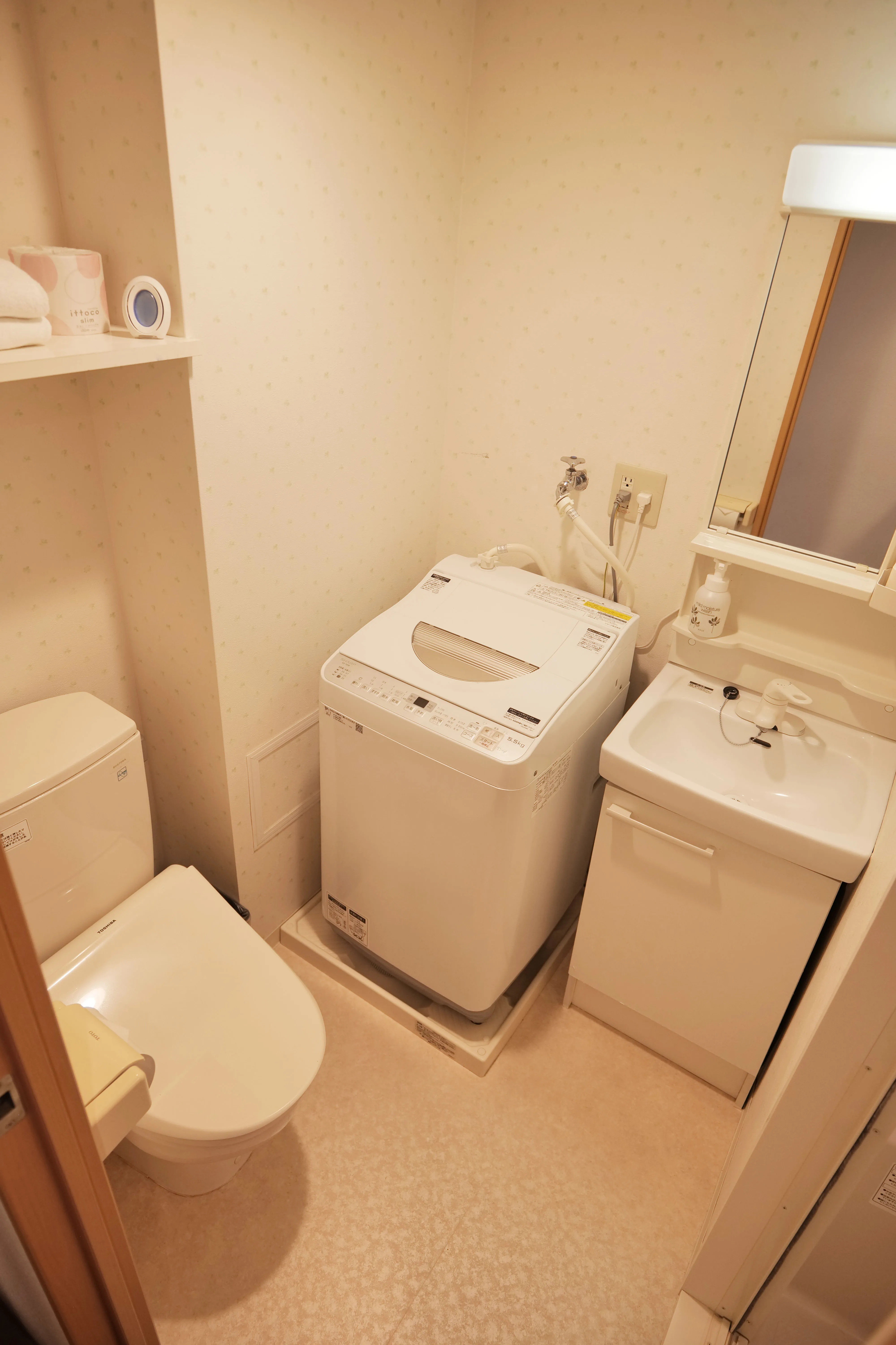 Compact Japanese-style toilet with built-in washlet functions, accompanied by a lavatory and washing machine for total convenience and cleanliness.