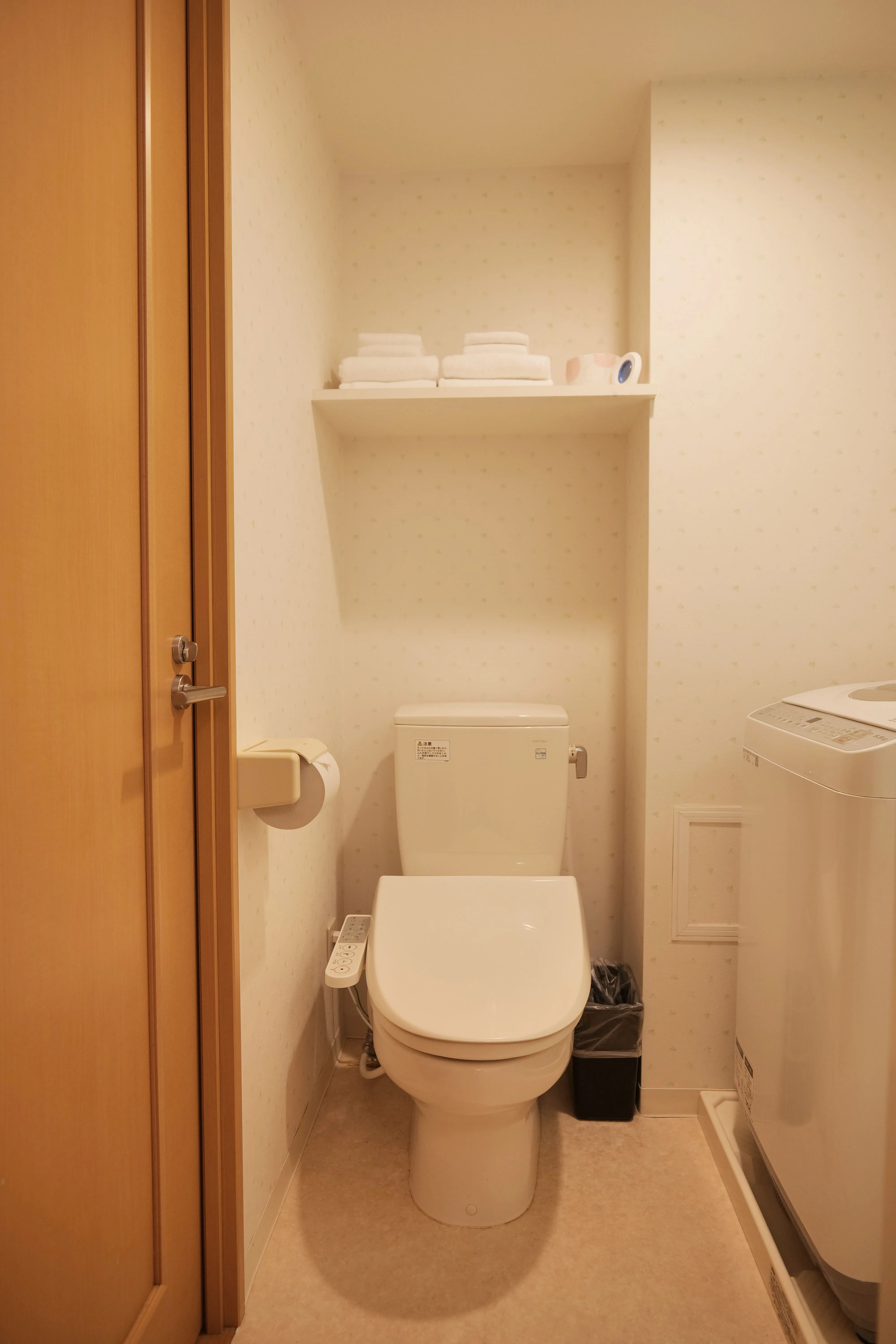 Compact Japanese-style toilet with built-in washlet functions, accompanied by a lavatory and washing machine for total convenience and cleanliness.