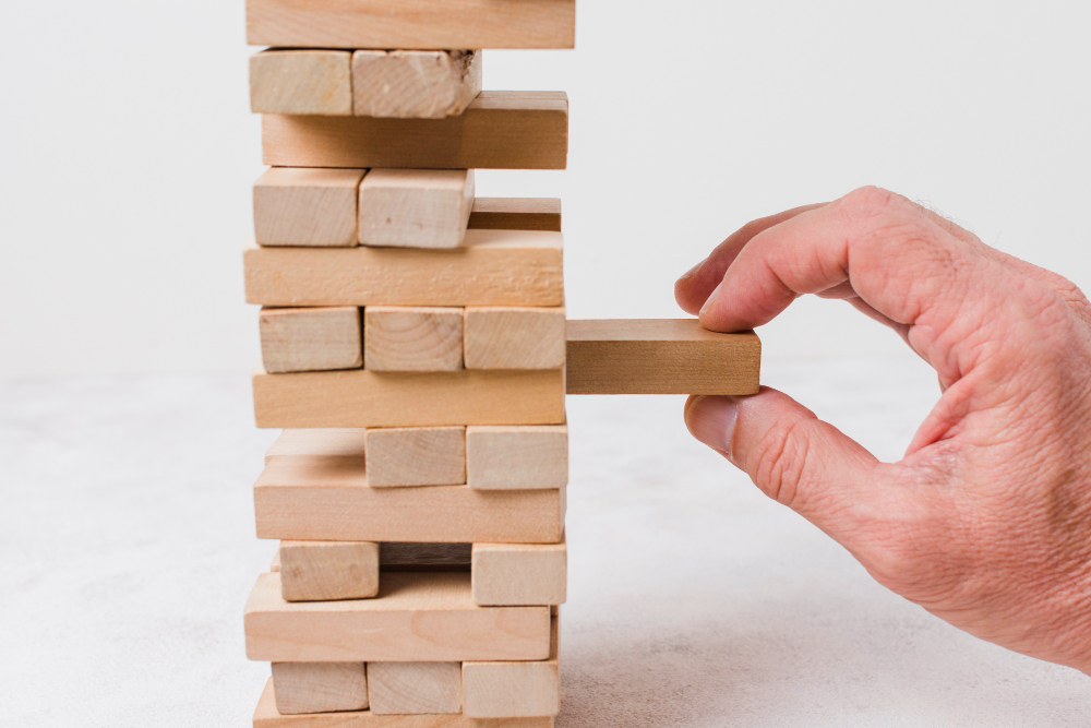 A hand building a structure with wooden blocks, representing the strategic construction of a lead base.