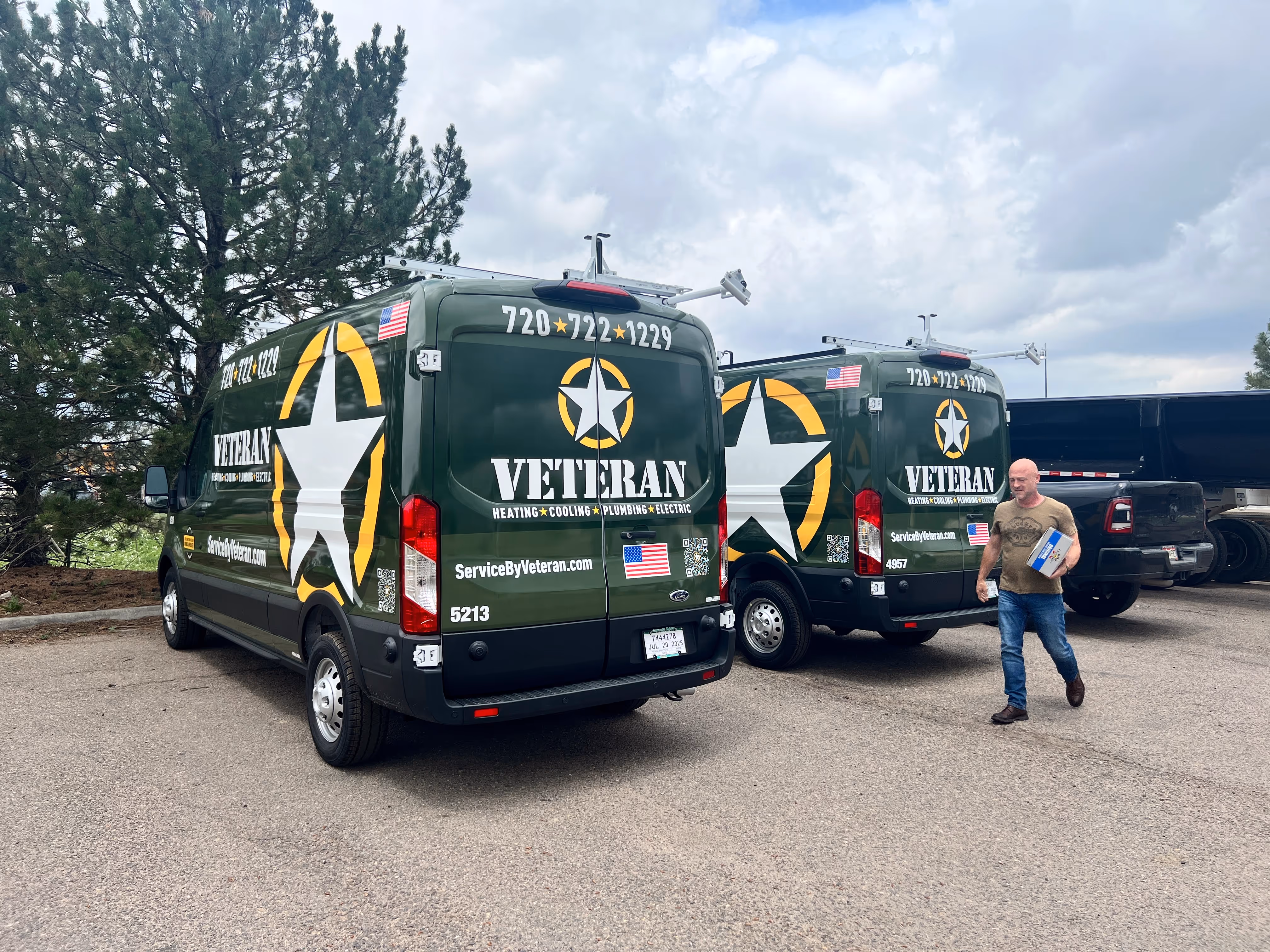 Two green service vans with military star logos and "VETERAN" branding are parked on a cloudy day.
