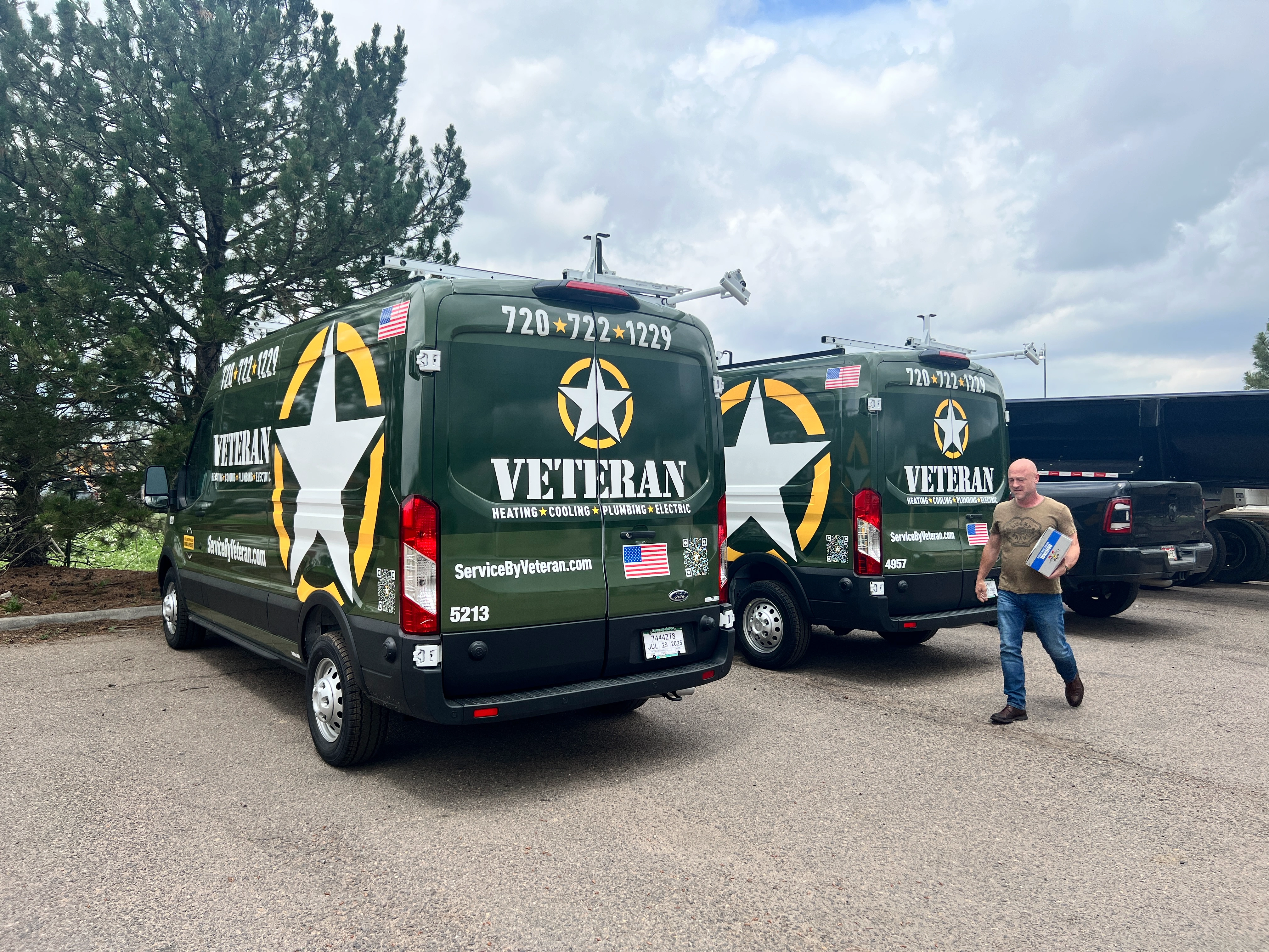 Two green service vans with white star logos and "Veteran" branding parked on a paved area. 