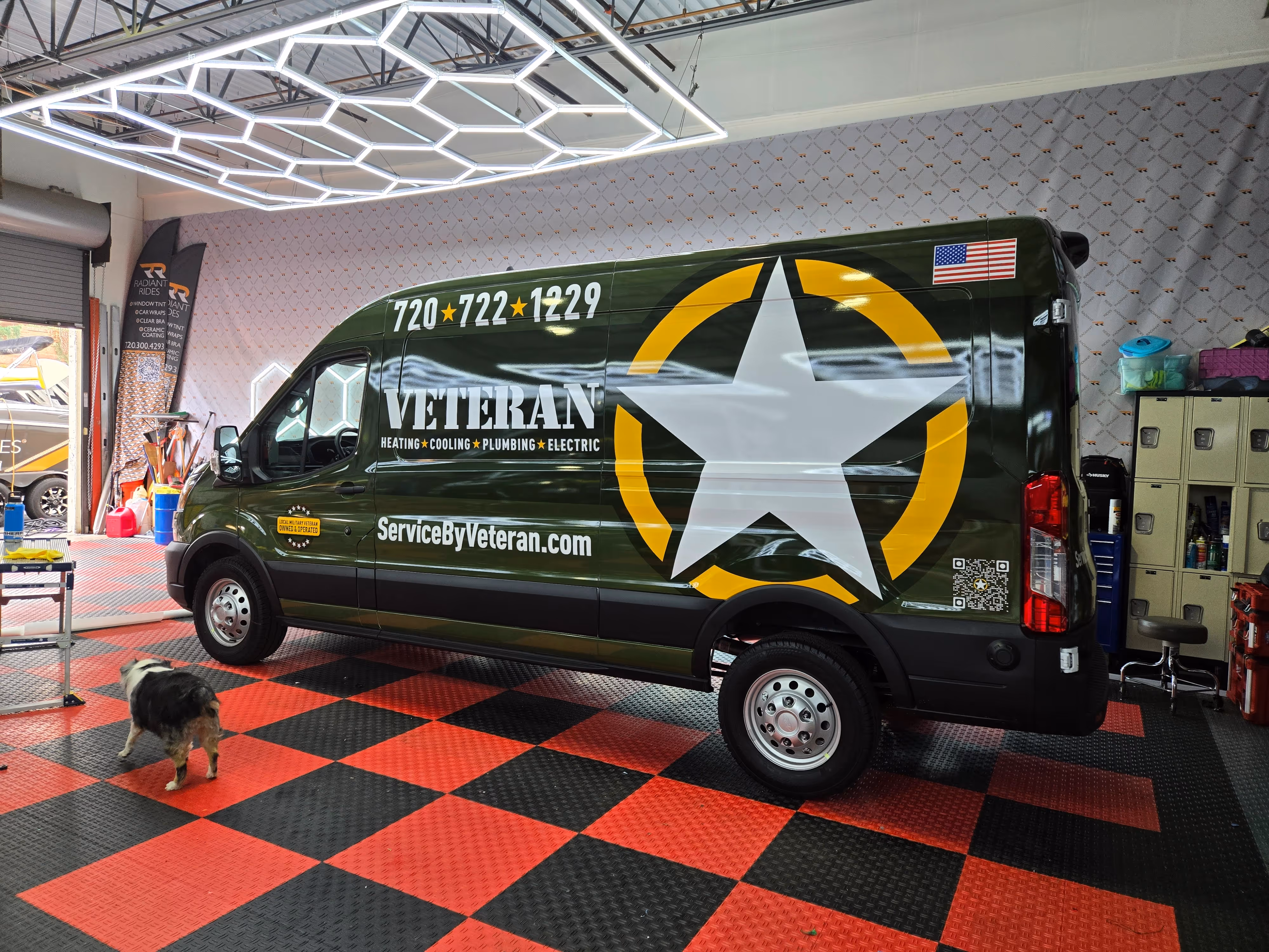 Green service van with a large white star logo and American flag parked on a red and black checkered floor.