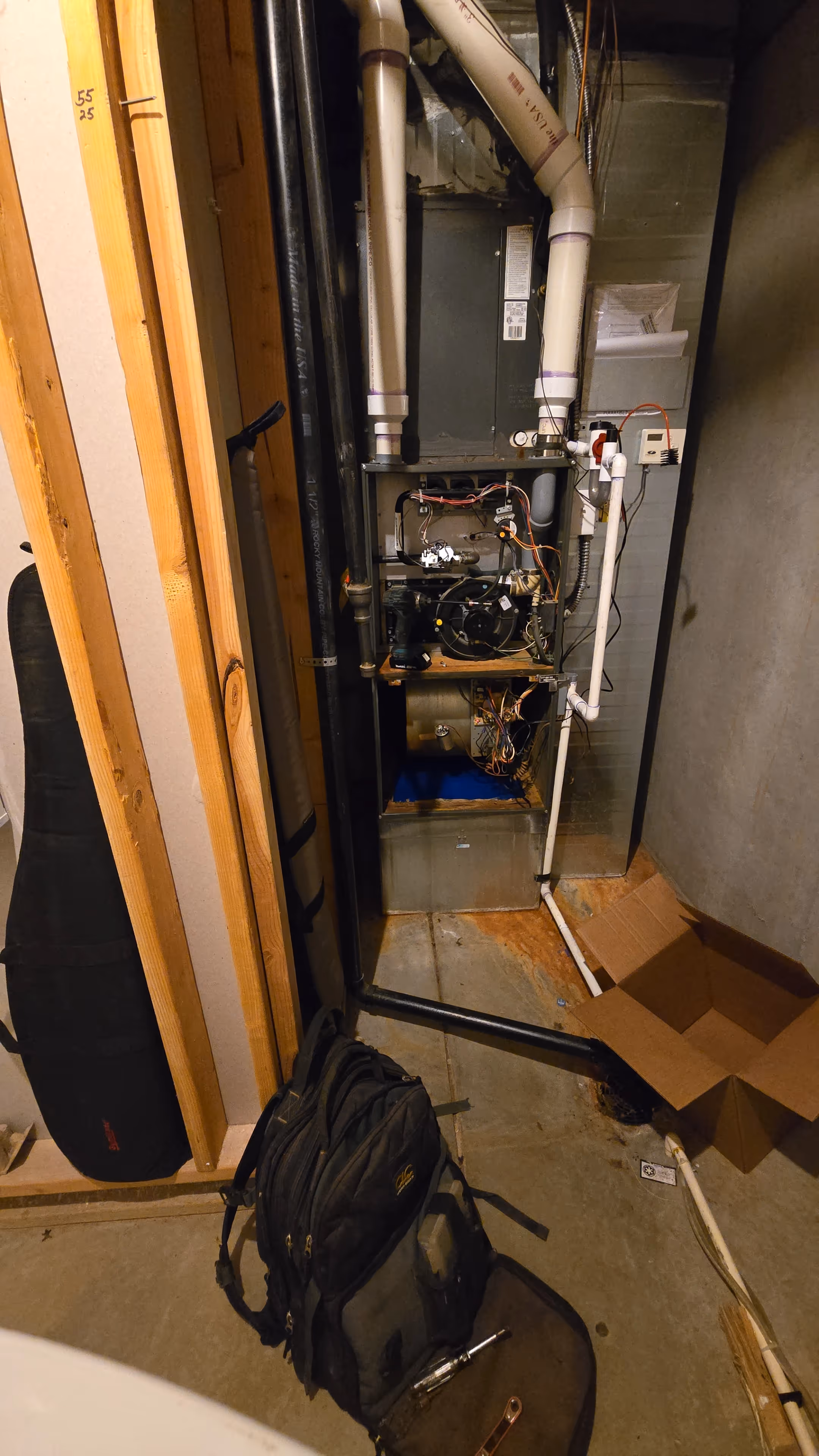Compact basement scene with an exposed HVAC system showing wires and pipes.