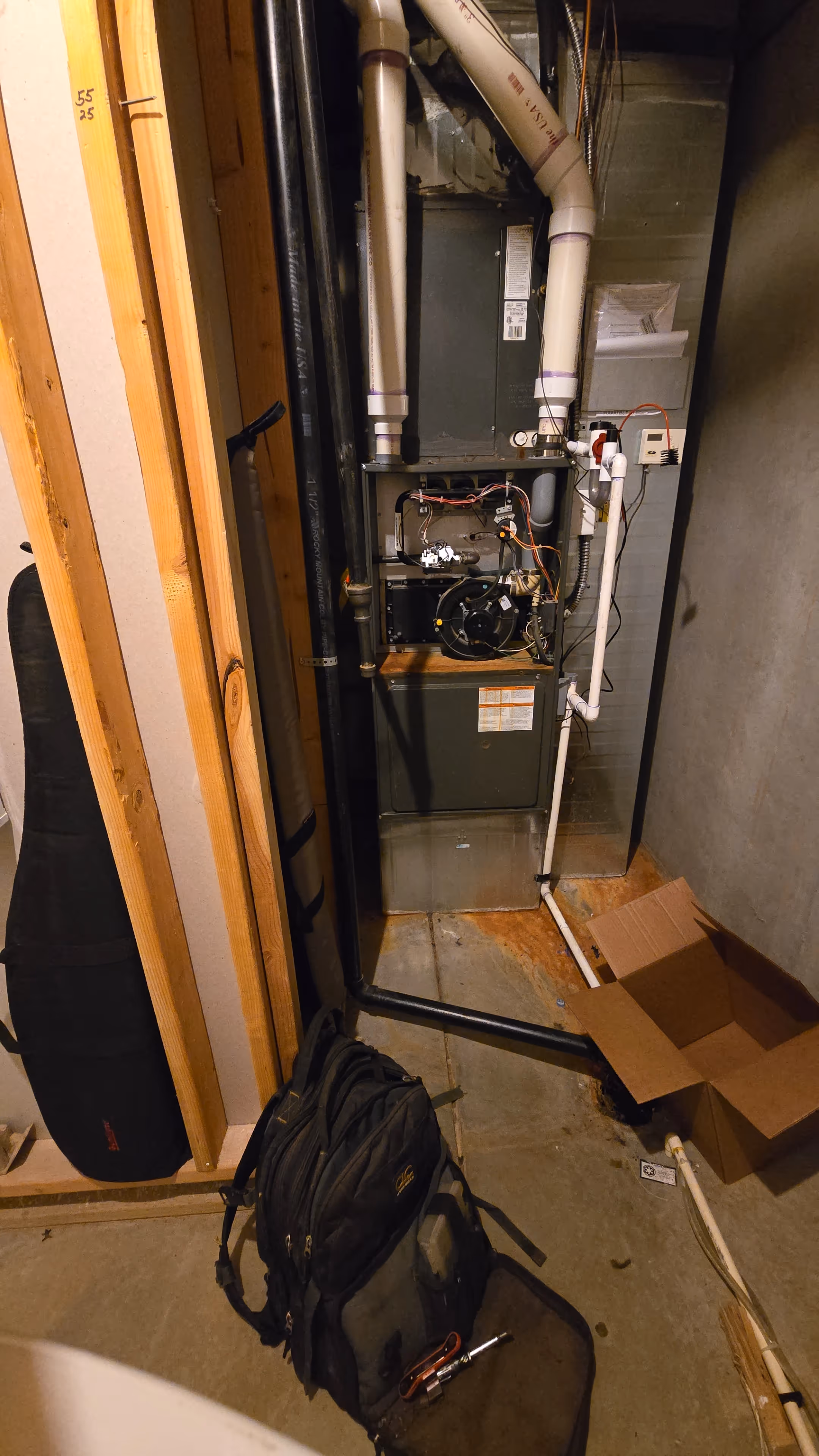 A room featuring a gas furnace and a bag of tools, highlighting a space for heating system maintenance or installation.