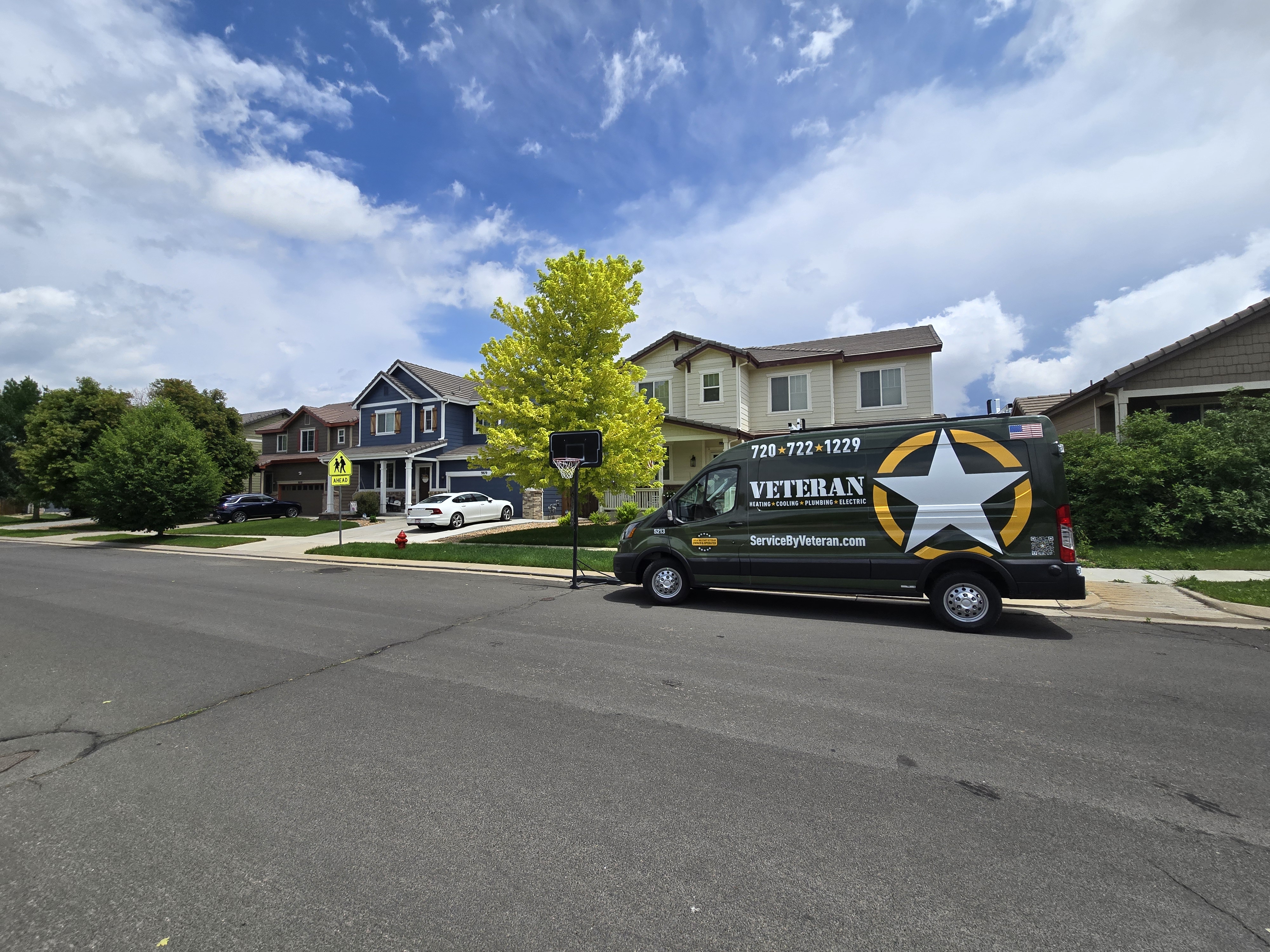 Two green service vans with business branding are parked on a red and black checkered floor in a well-lit auto workshop, creating a professional ambiance.