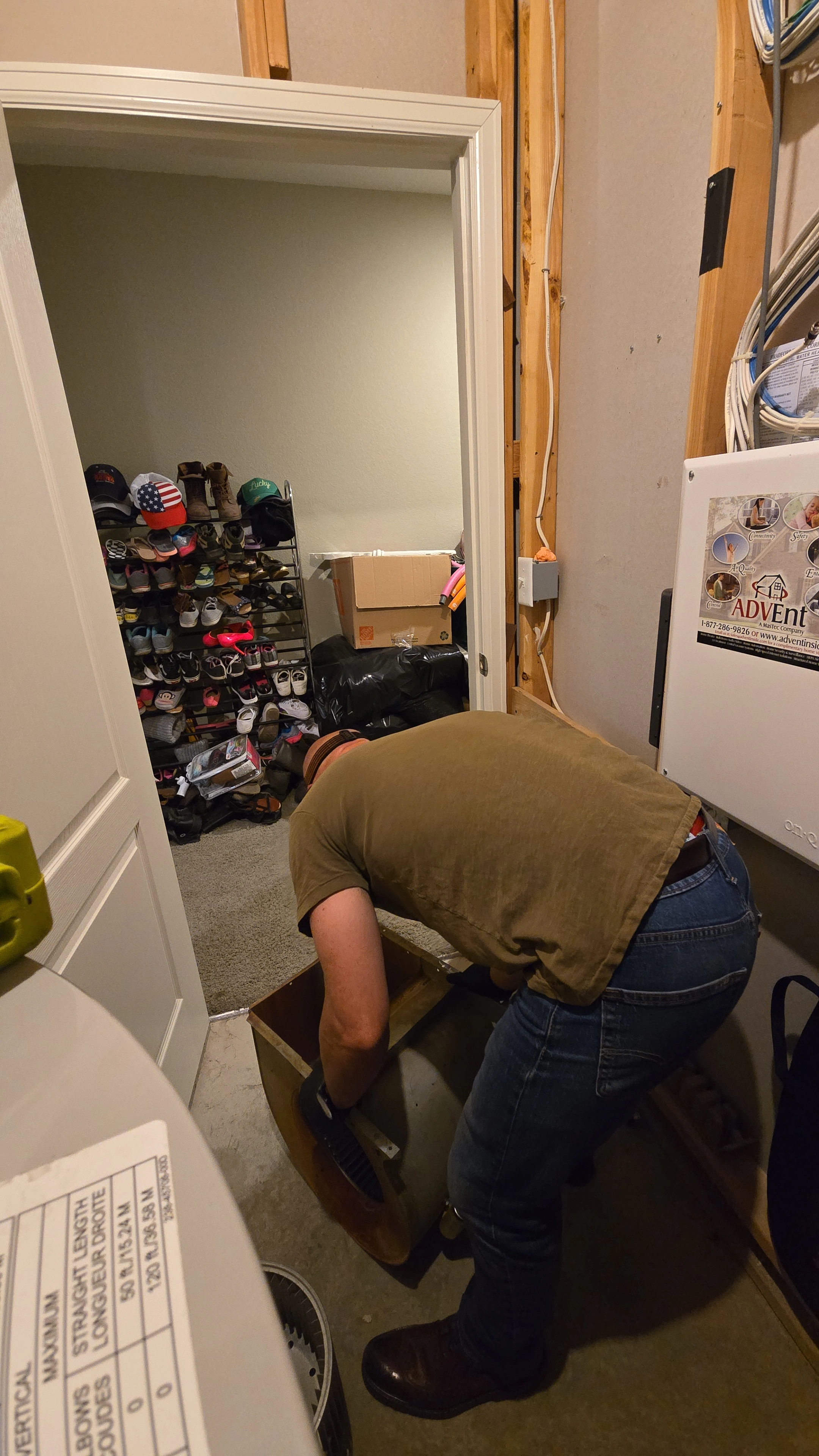 Una persona se inclina sobre una caja en una habitación desordenada con cableado expuesto.