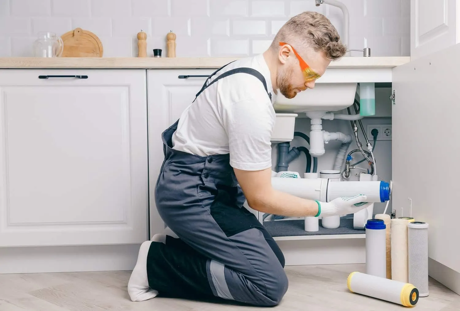 Plumber installing under-sink water filter.