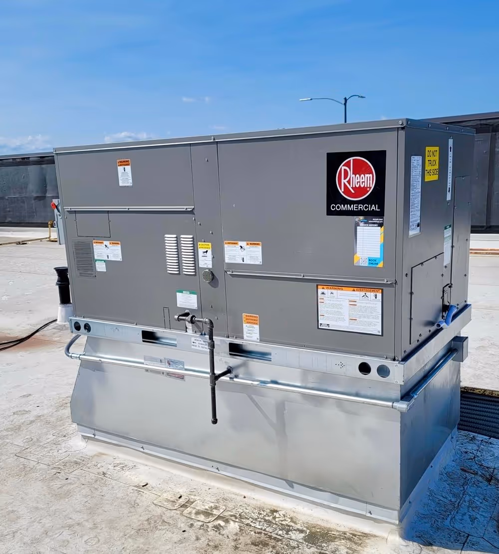 A large Rheem commercial air conditioning unit is installed on a rooftop.