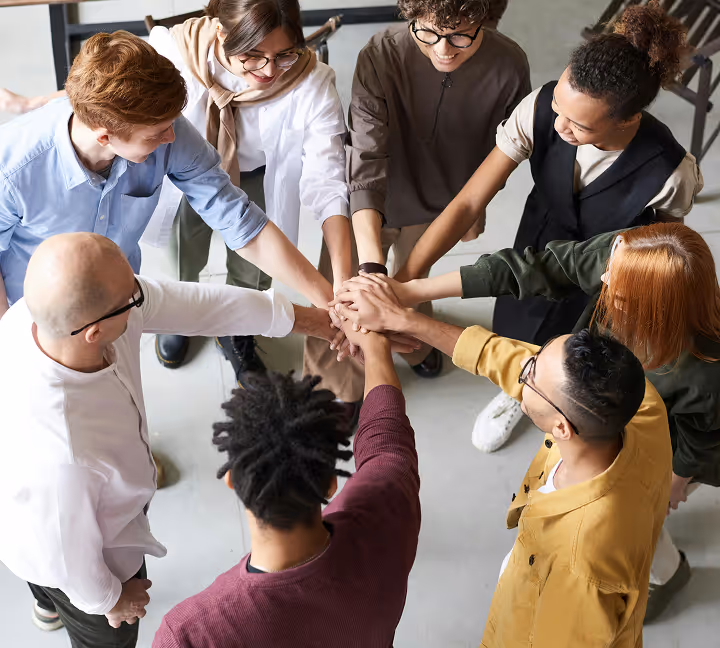 Business team standing in a circle with hands joined.