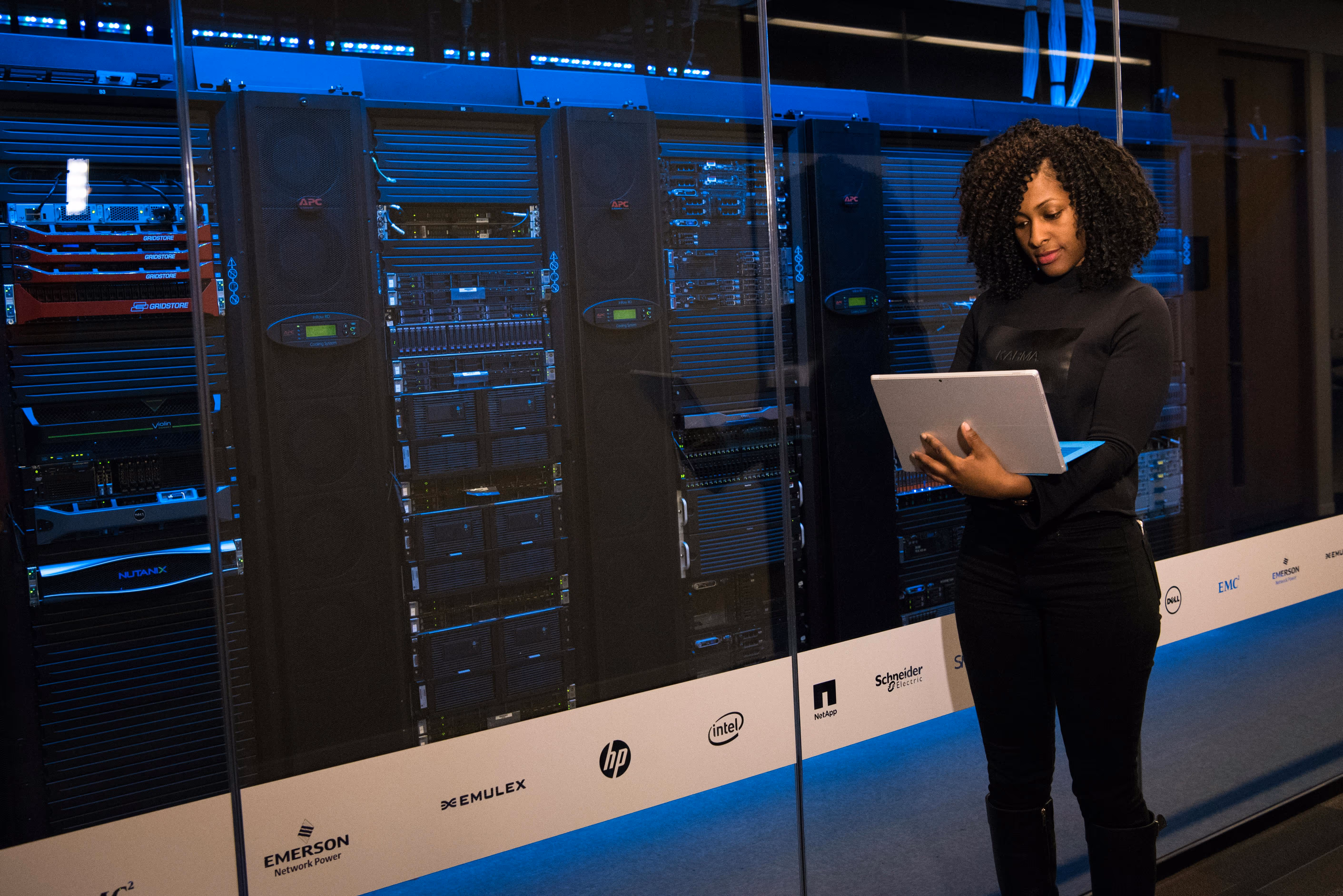 Person monitoring multiple server racks in a data center.