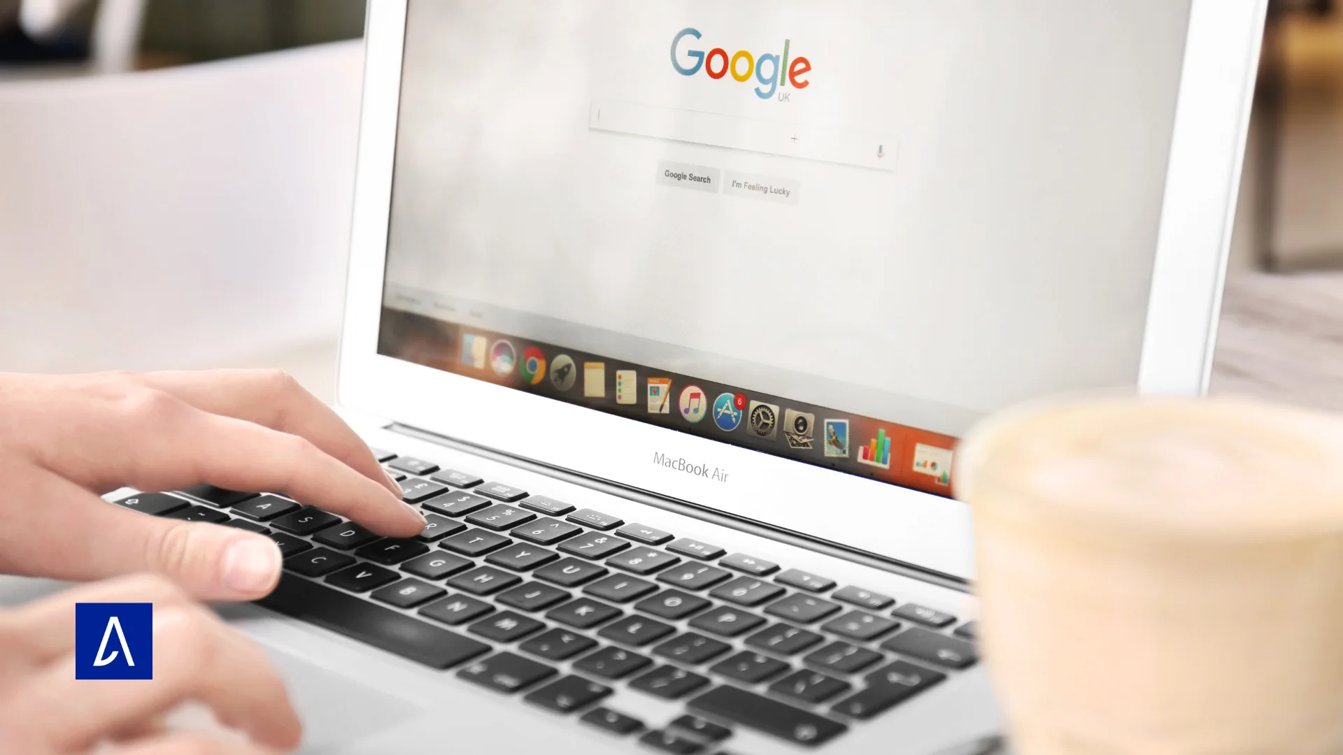 Recherche Google affichée sur un MacBook Air avec une main tapant au clavier