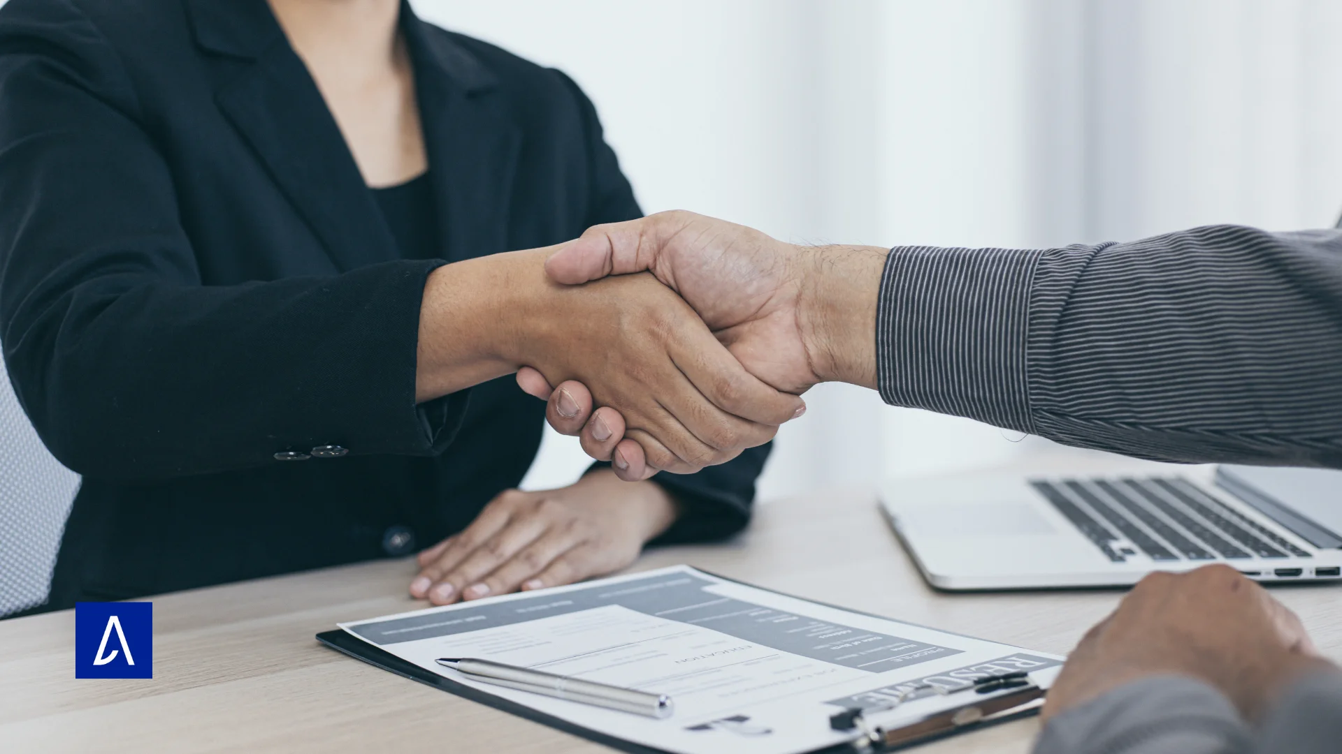 Deux personnes se serrant la main lors d’un rendez-vous professionnel avec un CV sur la table