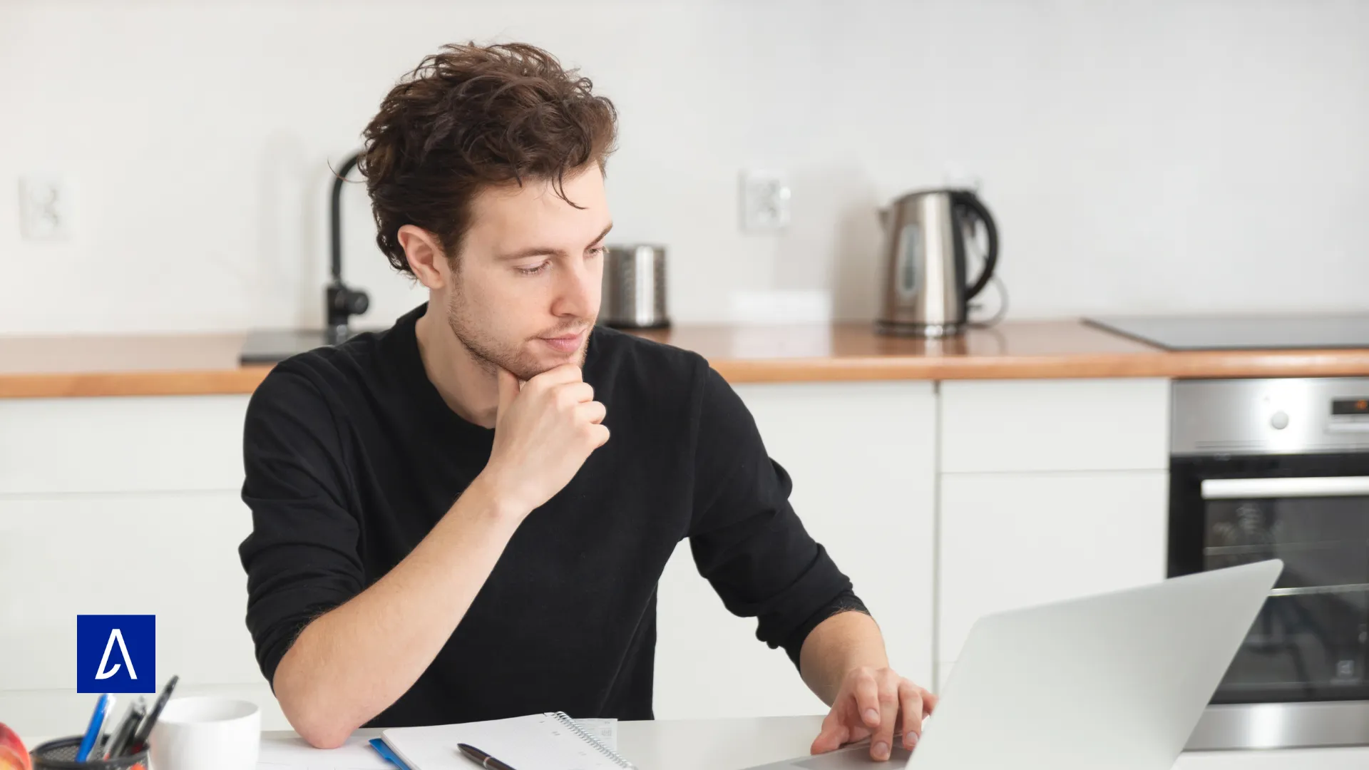 Étudiant en copywriting travaillant depuis chez lui sur son ordinateur portable, concentré sur ses notes.