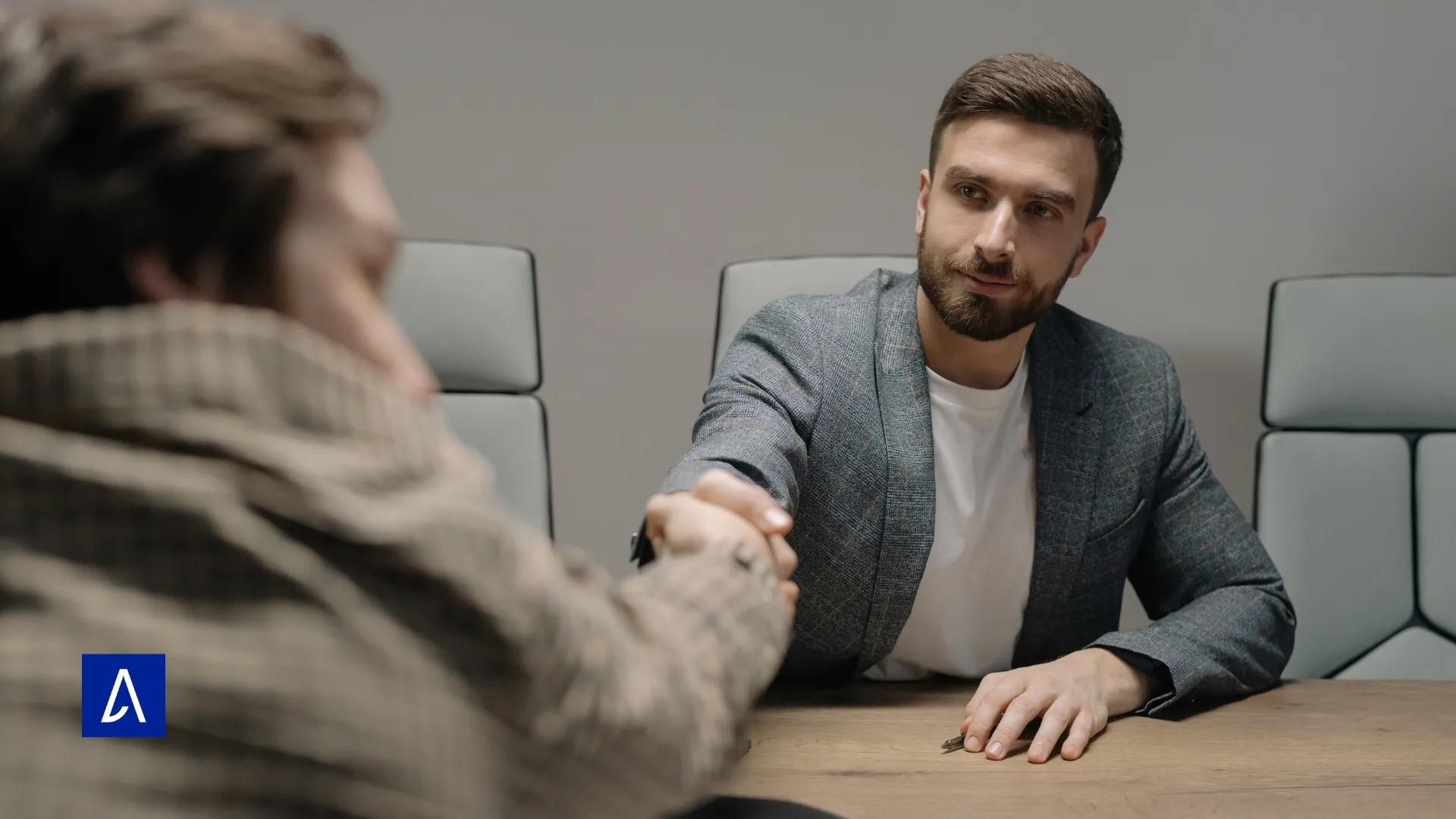 Deux hommes en réunion se serrant la main autour d’une table.