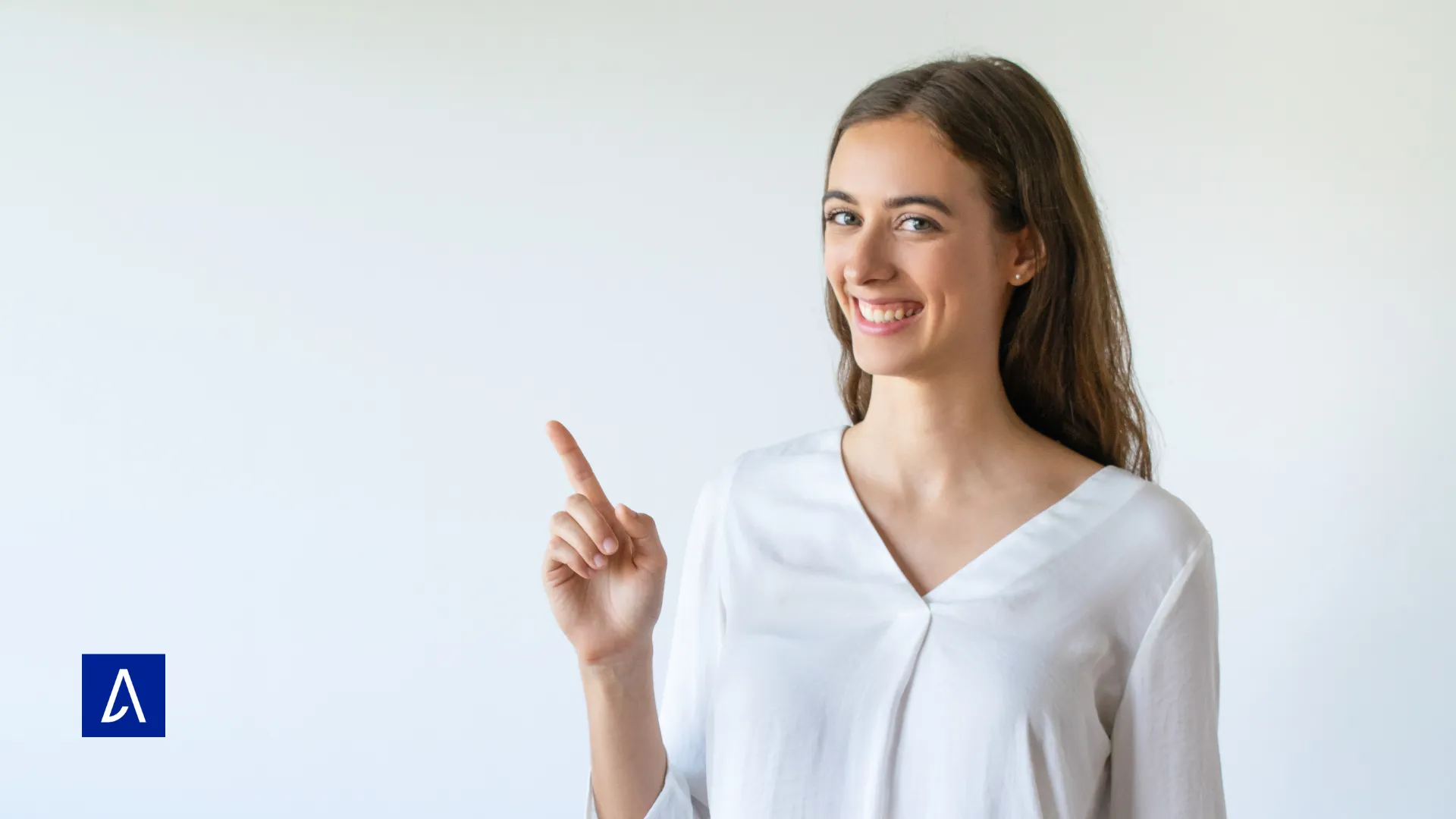 Femme souriante pointant du doigt vers un espace vide sur fond clair, représentant une idée ou une solution.