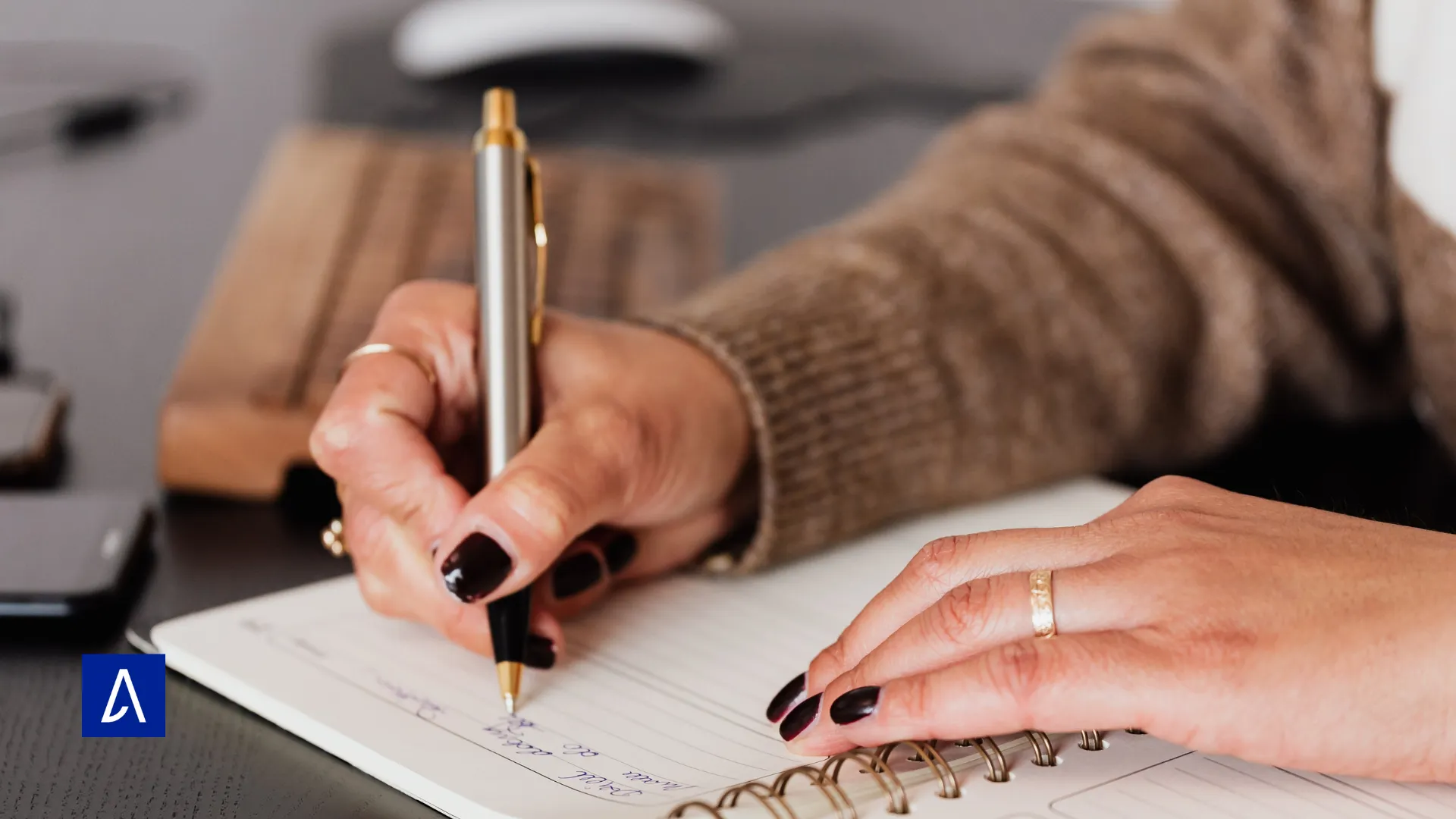 Mains d’une personne écrivant dans un carnet à spirales, symbolisant l’inspiration et le travail d’écriture concentré.