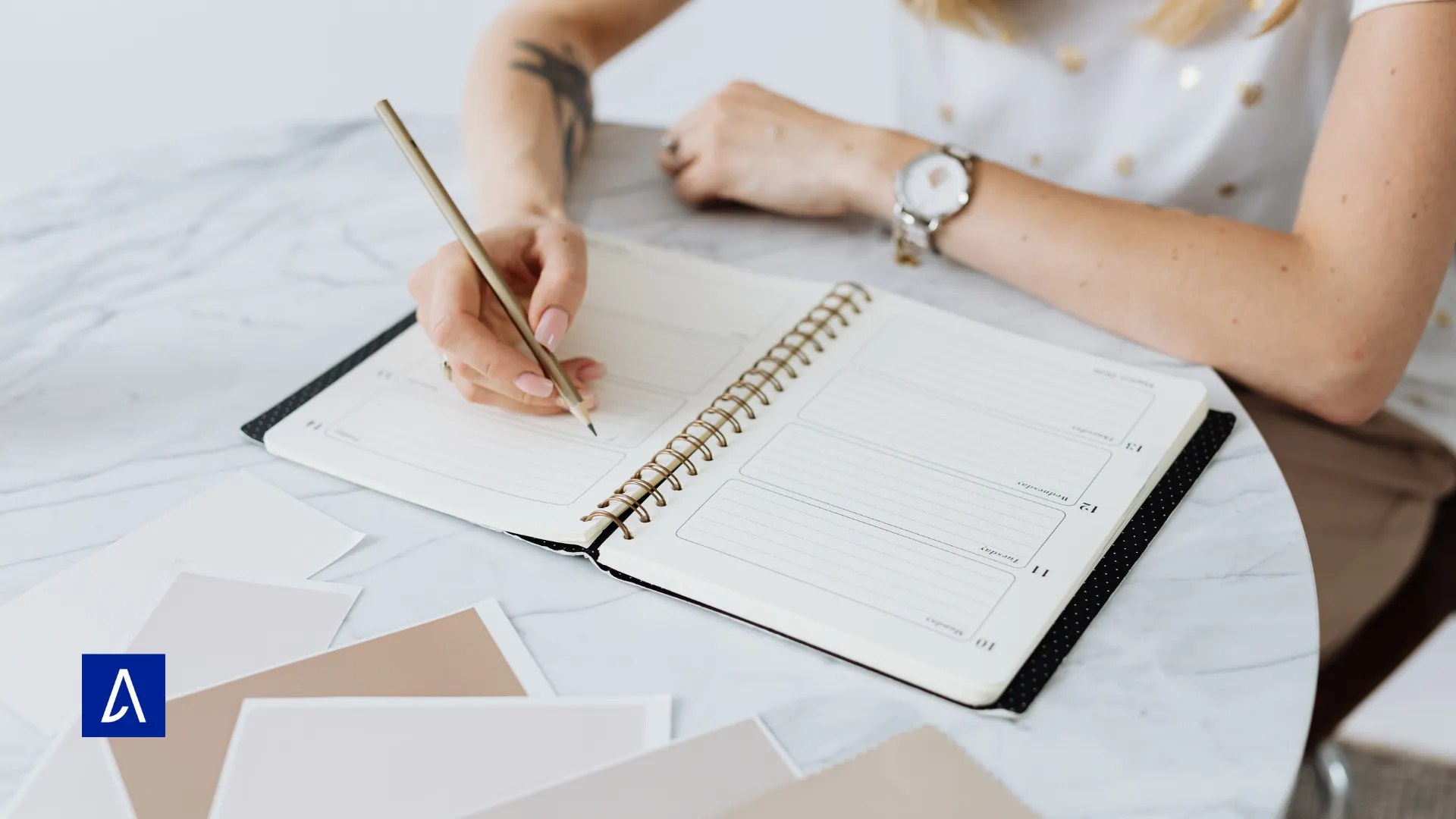 Femme écrivant dans un carnet de notes posé sur une table en marbre, représentant la planification et la créativité.