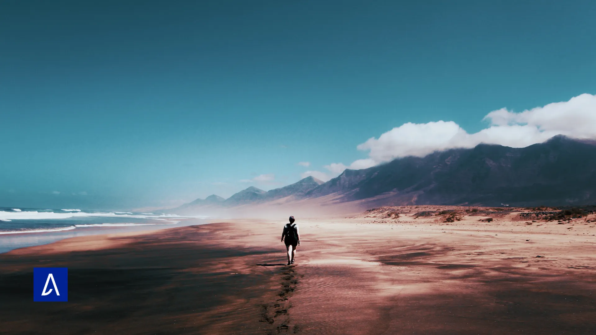Silhouette marchant seule sur une plage déserte bordée de montagnes, illustrant l’indépendance et la quête de sens.